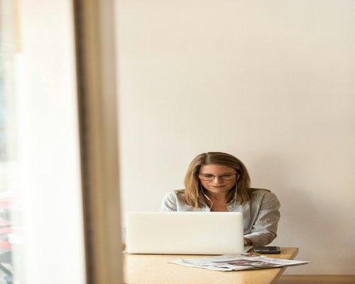 Woman looking away from her laptop out of a window